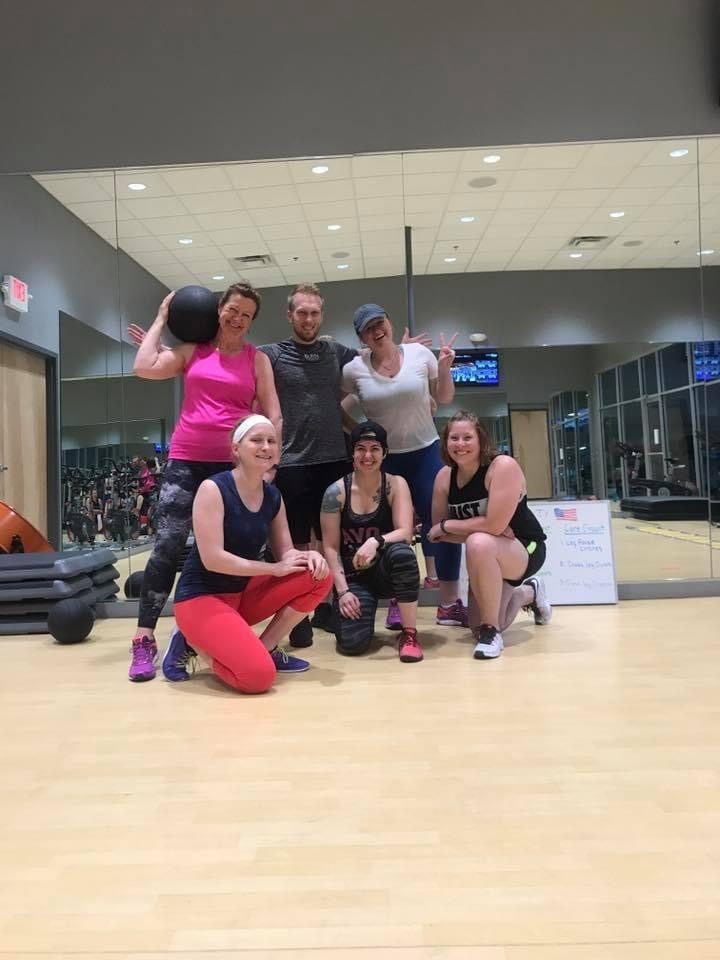 Six people gathered together after a group class in a studio, smiling at the camera