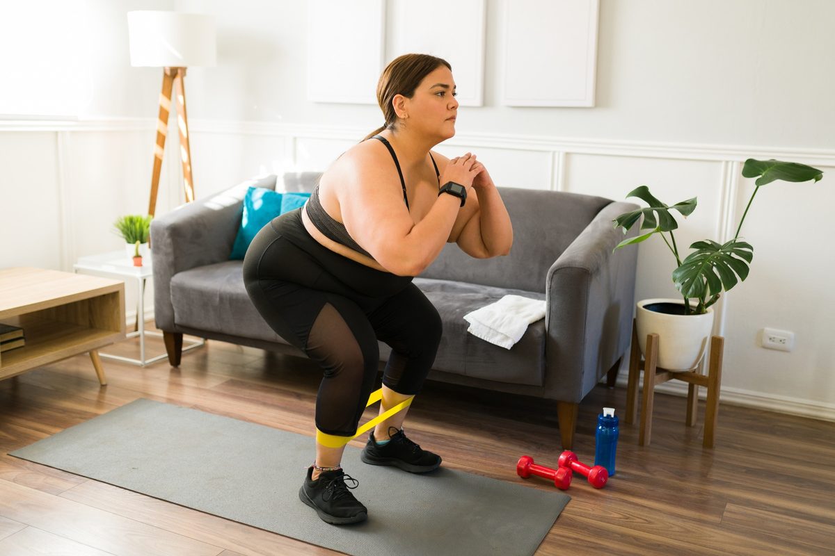 Woman squatting with a resistance band in her living room