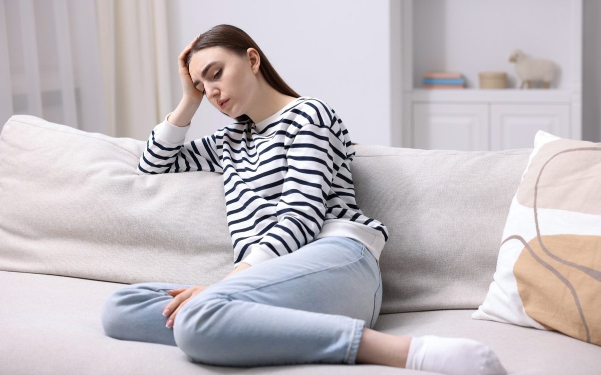 A woman sitting on a couch with her head resting on her hand, worn out